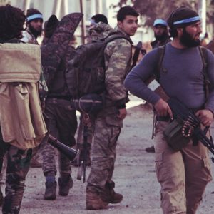 A gunman carrying a machine gun, with other gunmen in the background. A gunman carrying a machine gun, with other gunmen in the background.